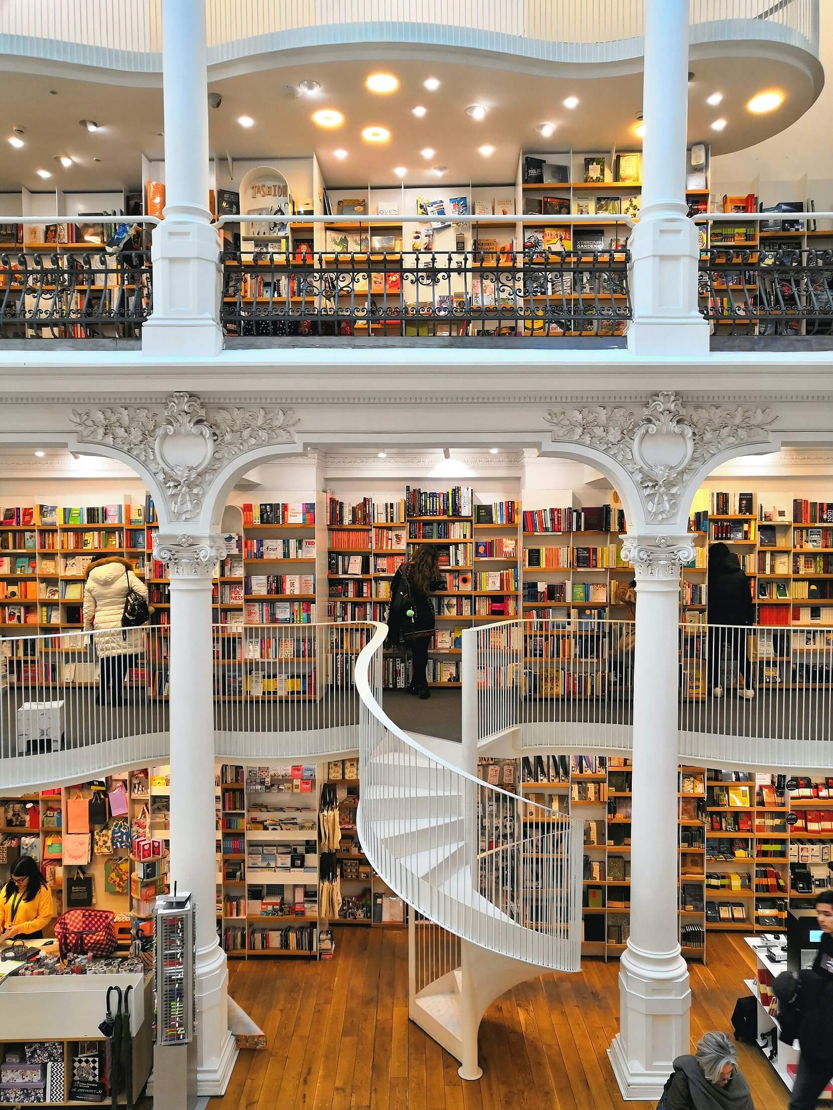 Beautiful library with lots of books on different floors and a spiral staircase