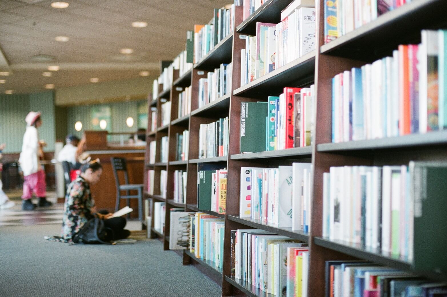 Bookshelf with an indoor seating and study area behind in the distance.