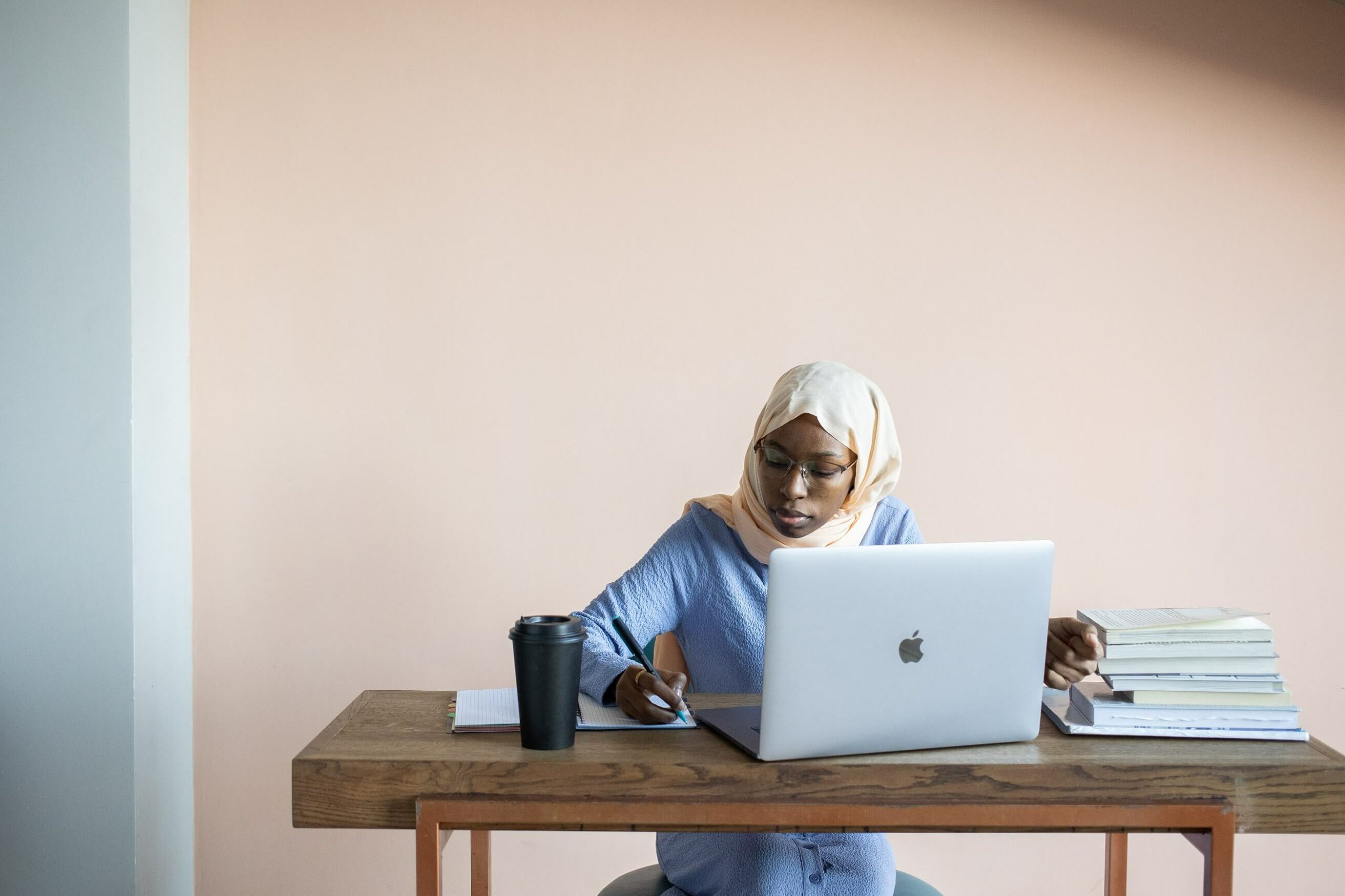 Woman sat at a desk reading computer screen and making notes