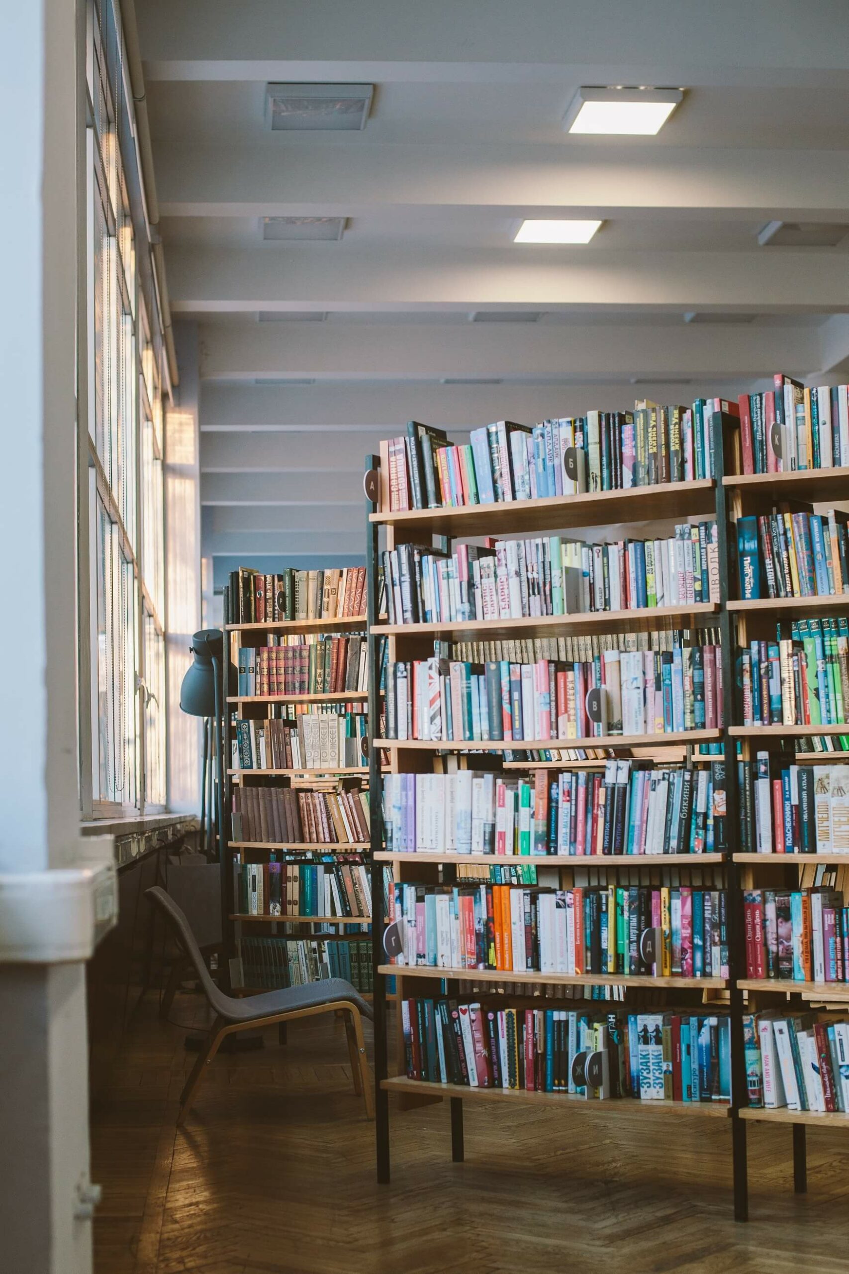 Library full of loads of colourful books, with a table and reading area